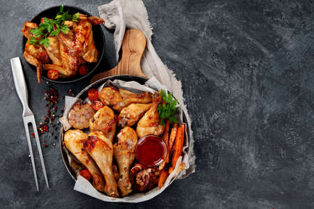 Roasted chicken legs with garlic and sauce on gray background. Homemade food concept. Top view, copy spaceの写真素材