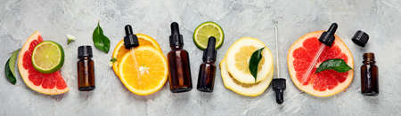 Bottle of essential aroma oils with citrus on light gray background. Top view, flat lay, panorama, bannerの写真素材