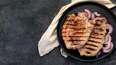 Sliced roasted pork meat on dark gray background. Organic gourmet food concept. Top view, flat lay, copy spaceの写真素材