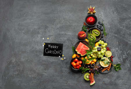 Christmas tree made of fruits on dark background. New Year Holidays concept. Top view, flat lay, copy spaceの写真素材