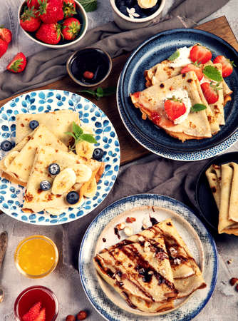 Sweet crepes assortment with berries chocolate on gray background. Homemade food concept. Top view, flat layの写真素材
