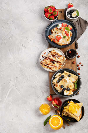 Sweet crepes assortment with berries chocolate on gray background. Homemade food concept. Top view, flat lay, copy spaceの写真素材