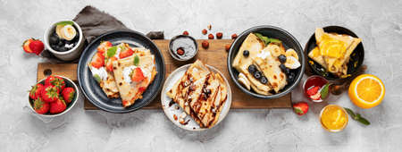 Sweet crepes assortment with berries chocolate on gray background. Homemade food concept. Top view, flat layの写真素材