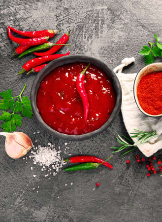 Spicy hot chilli tomato sauce on gray background. Traditional hot sauce concept.の写真素材