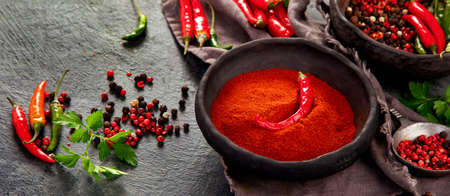 Red chili or chilli cayenne pepper a nd peppercorns on dark background. Traditional spices concept. Top view, flat lay, copy spaceの写真素材