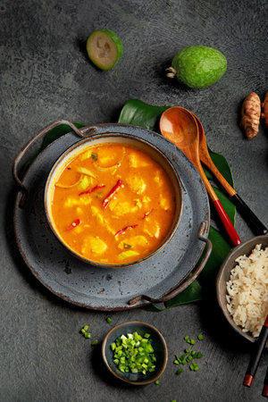 Yellow curry with chicken in bowl on dark background. Traditional Asian food. Top view, flat lay,...