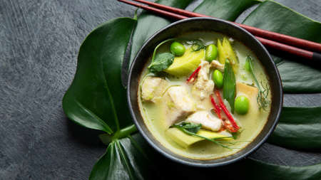 Green curry with chicken in bowl on dark background. Traditional Asian food. Top view, flat lay,...