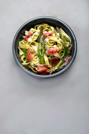Pasta with asparagus and prosciutto on gray background. Traditional Italian Food concept. Top view, flat lay, copy spaceの写真素材