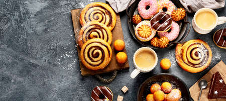Table with various cookies, donuts, cakes and coffe cups on dark backround. top view, copy spaceの写真素材