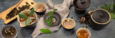 Asian tea set on dark background. Plant leaves, natural herbal tea composition. panorama