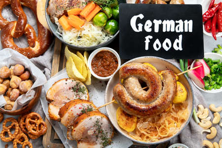 Traditional German cuisine, Schweinshaxe roasted ham hock. Beer, pretzels and various Bavarian specialties on wooden board, white backgroun, top view.の写真素材