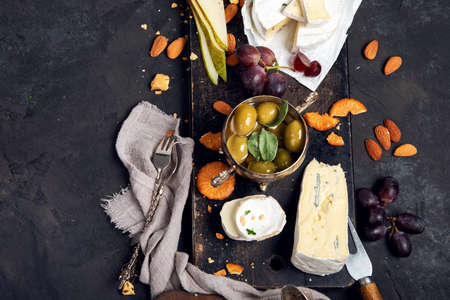 Cheese board on dark background. Celebration meeting. Food for wine, snacks, delicatessen.の写真素材