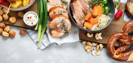 Traditional German cuisine, Schweinshaxe roasted ham hock. Beer, pretzels and various Bavarian specialties on wooden board, white backgroun, top view.の写真素材