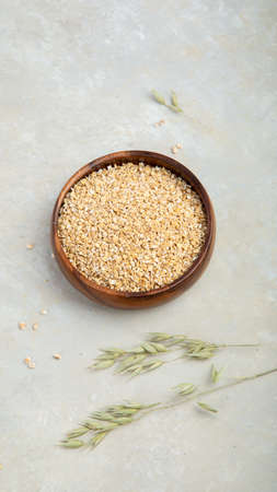 Dry oatmeal in bowl on light background. Healthy breakfast. Dieting and weight loss concept. Flat...