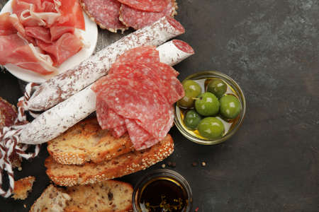 Sasusages assortment on dark background. Meat product made of finely chopped and seasoned meat. Flat...