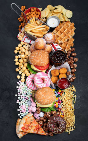 unhealthy products. food bad for figure, skin, heart and teeth. Assortment of fast carbohydrates food with fries and cola on a dark background. top view.の写真素材