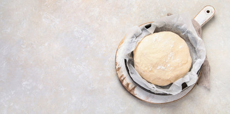 Raw dough pastry in a bowl on neutral background. Homemade bio food concept. Top view, copy space,...