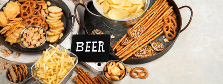 Assortment of beer and salty snacks on light background. party food concept. copy space, panoramaの写真素材