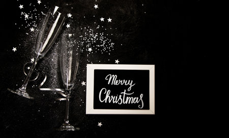 Two champagne glasses. Christmas decoration on a black background. Happy New Year Celebration. top...