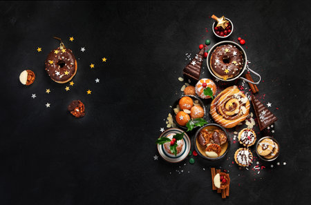 Christmas tree with sweets and cookies decoration on dark background. holiday food. top view, copy...
