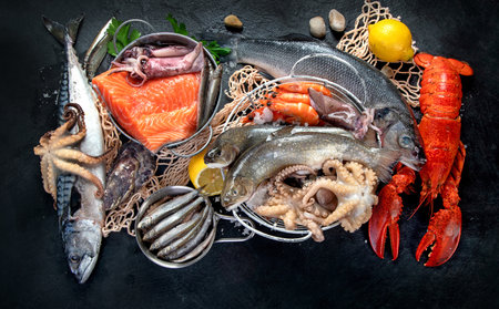 Fresh fish and seafood assortment on black background, fish market. Healthy diet eating concept. top...