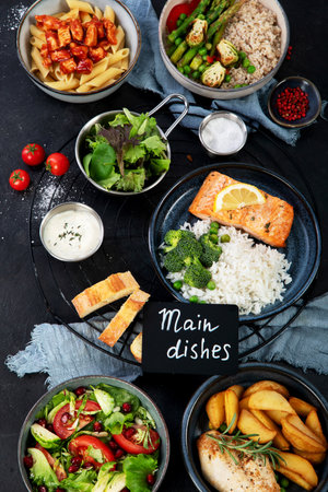 Set of various main dishes. Different healthy main courses, meat and fish dishes, pasta, salads, sauces, bread and vegetables on a dark background. top view.の写真素材