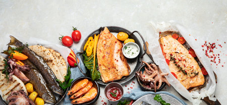 Seafood platter. Assorted delicious seafood with vegetables on a gray background. top view. Panorama with copy space.の写真素材