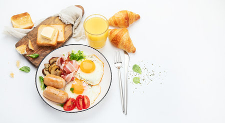 English breakfast with fried egg, sausage, bacon and toast on white background, top view, copy spase