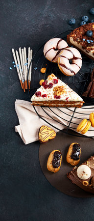 Table with various cookies, donuts, cakes, cheesecakes on dark background. Delicious dessert table. Top view, flat layの写真素材