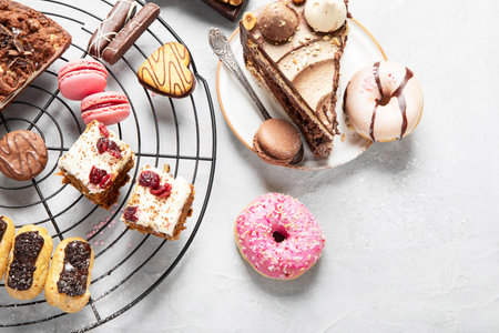 Table with various cookies, donuts, cakes and coffe cups on light backround. top view.
