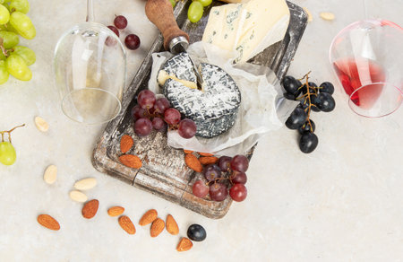 Pink and red wine served with cheeses, nuts, grapes and glasses of wine. Delicious food wine snacks assorted served on boards. Flat lay on a white background. Panorama with copy space.の写真素材