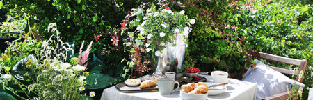 Continental breakfast on the garden table. Country lifestyle or weekend morning concept. Peaceful rural scenery. panorama.の写真素材