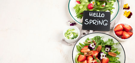 Delicious spring salads with edible flowers, vegetables, fruit, microgreens and cheese on a white background. Clean and healthy eating concept. top view. Panorama with copy space.の写真素材