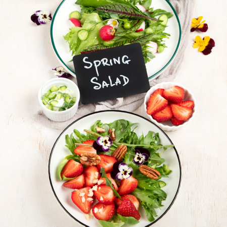 Delicious spring salads with edible flowers, vegetables, fruit, microgreens and cheese on a white background. Clean and healthy eating concept. top view.の写真素材