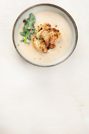 Creamy cauliflower soup with nuts and herbs in a bowl on a light background background. top view. copyspace.の写真素材