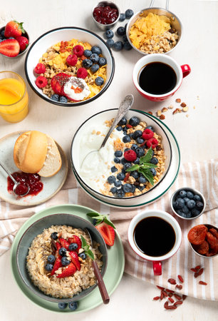 Breakfast food table. Healthy breakfast or brunch set, meal variety with granola, porridge, cornflakes, fresh berries, fruits and various of toppings on a white background. top view.の写真素材