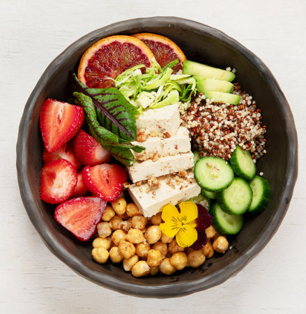 Healthy vegan lunch bowl. Avocado, quinoa, cucumber, red orange, chickpea, cheese, salad and strawberries on a white background. top view.の写真素材