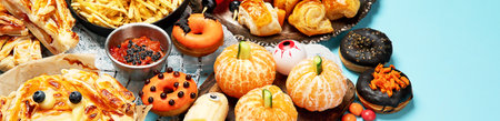 Fun Halloween dinner party table scene on a blue background. top view. Pizza, pie, spaghetti and snacks.の写真素材