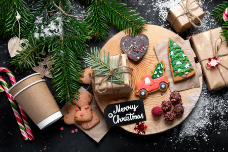 Christmas mix cookies, traditional Xmas chocolate Gingerbreads with holiday decoration, gifts, Christmas tree branch on dark backgrount, top view.の写真素材