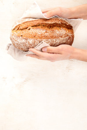 Baker or cooking chef holding fresh baked bread in hands on a light background. Concept of cooking....