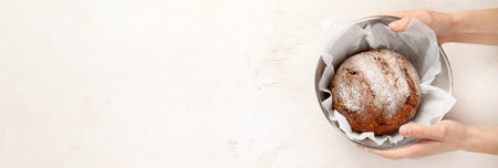 Baker or cooking chef holding fresh baked bread in hands on a light background. Concept of cooking....