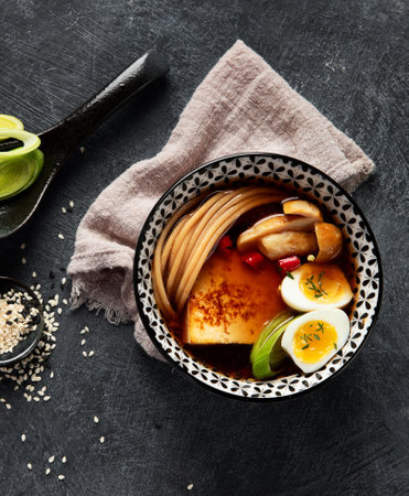 Asian soup with egg, tofu, mushrooms and onion on black background. Traditional food concept. Top view, copy space.の写真素材