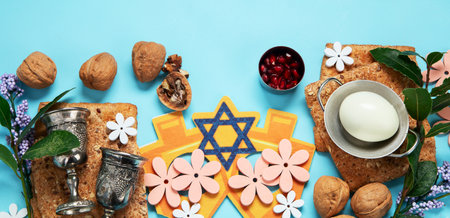 Passover celebration concept. Matzah, red kosher walnut and spring beautiful flowers on a blue background. Traditional ritual Jewish bread. Panorama.の写真素材