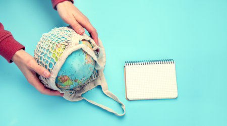 Hand holding globe on blue background. Environment protection. Top viewの写真素材