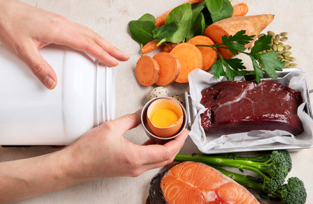 Vitamin A in food, natural products rich in vitamin A as red pepper, parsley leaves, dried apricots, carrots, broccoli, milk, egg yolk and cod liver oil on a light background. Top view. Panorama.の写真素材