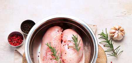 Chicken breast raw with rosemary and red pepper on wooden background. Top viewの写真素材
