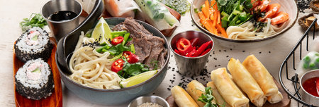 Assorted Asian meal, vietnamese food. Pho bo, noodles, spring rolls, sauces. Top view. Panorama with copy space.の写真素材