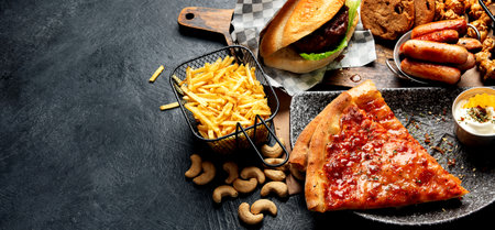 Fast food on a dark background. Junk food for your heart and skin. Trans fat concept. Copy spaceの写真素材