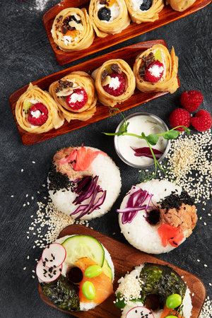 Hybrid trendy food on dark background. Sushi roll pancake, donut sushi, pizza with pasta. Top viewの写真素材