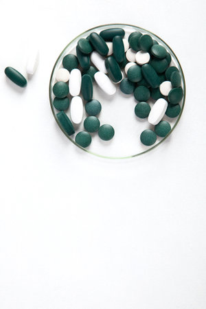 Various colorful pills in petri dish isolated on white, top view. Healthcare support. Pharmacy lab and pharmaceutical research concept. Copy space.の写真素材